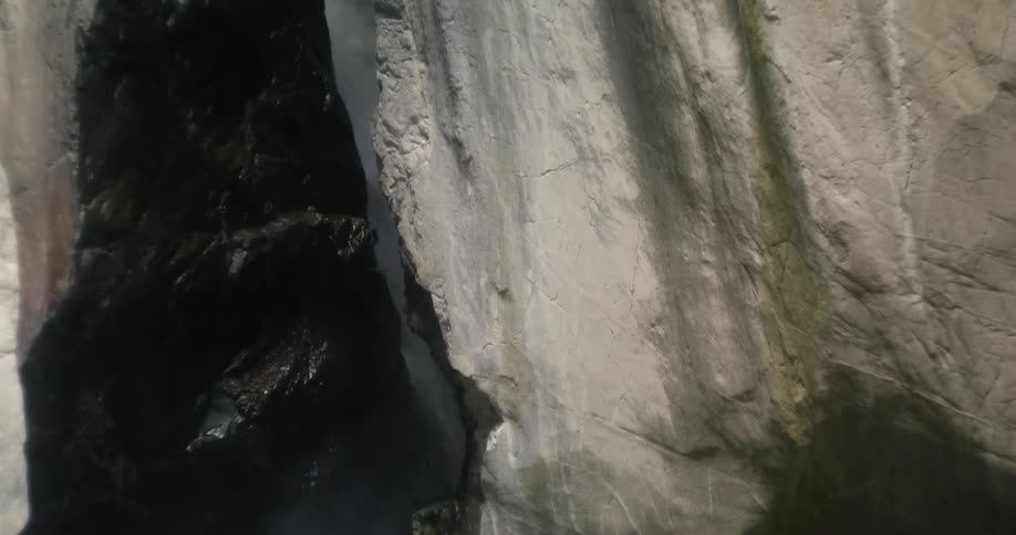 Water is falling behind large rocks of a mountain and collecting at the bottom in the daytime