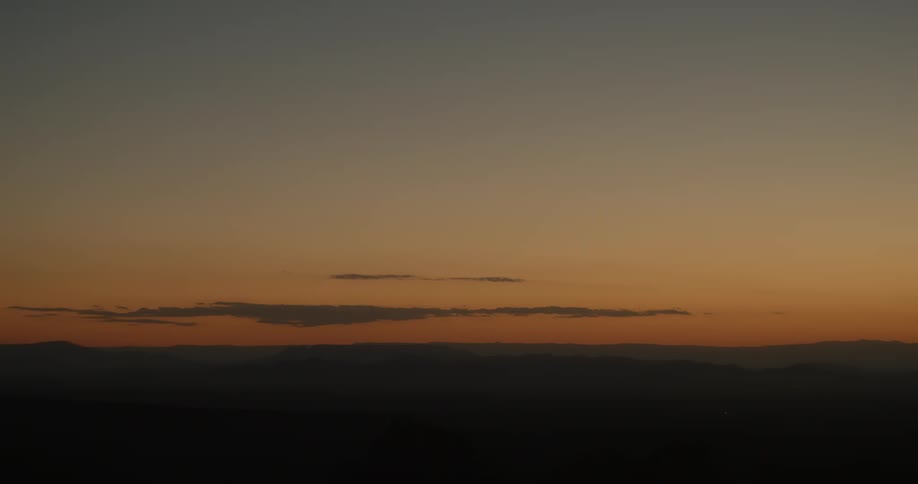 Placid orange yellow dark sky at sunset over the plains and mountains