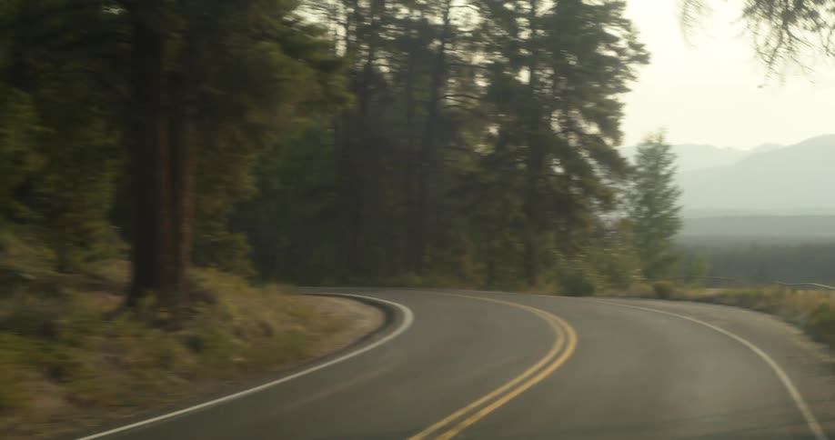 Traveling on a forest road and around the curve there are mountains in the distance