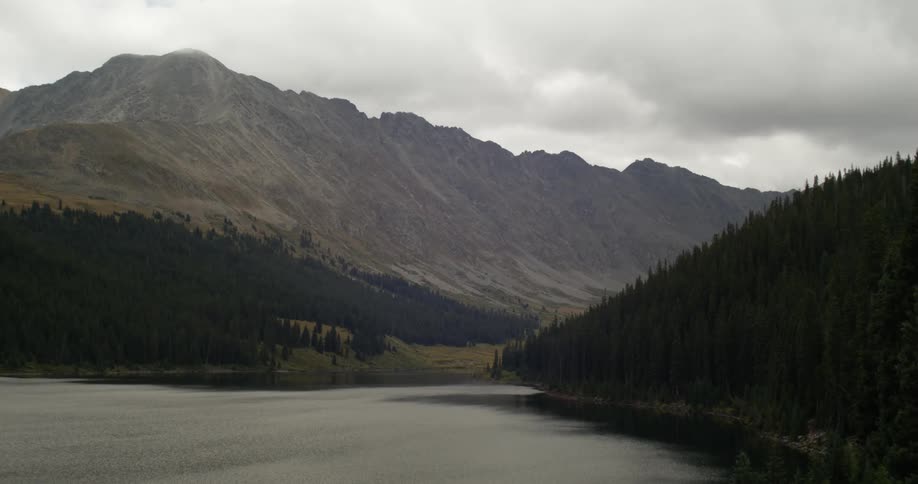 Lake near the pine tree forest in the mountains at evening