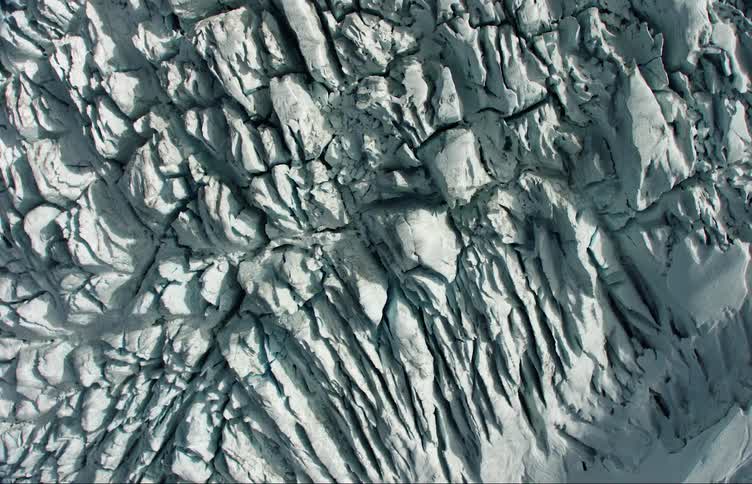 Dark crevices contrast with white of ice on glacial terrain