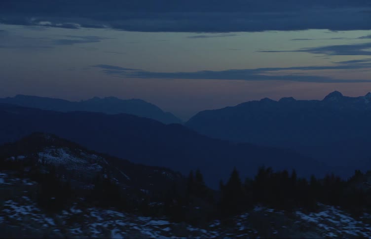 Aerial view of the snow covered slopes of a mountain range at sunset