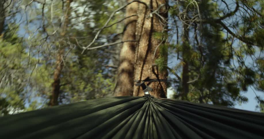 A hammock swinging on trees with the sky and clouds in the background