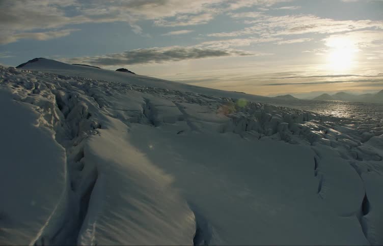 Aerial view of the snow and ice landscape near the mountains at sunset
