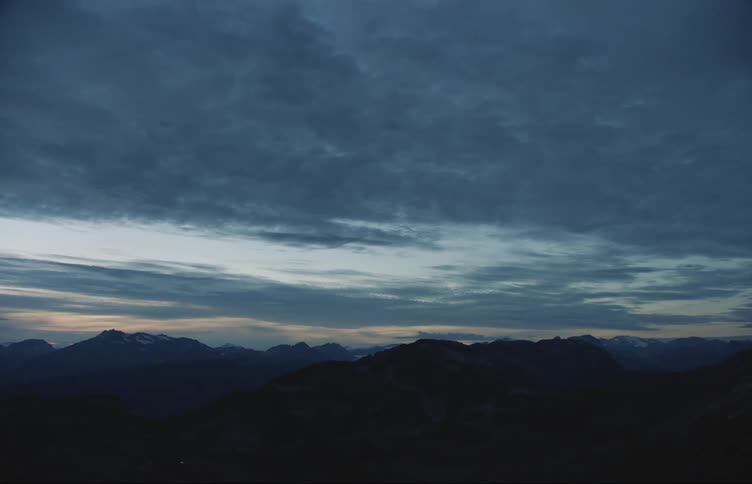 Dark blue clouds in the evening sky over the silhouettes of mountains