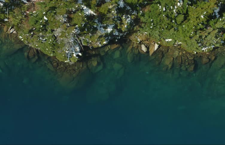 Aerial top down view of the green and blue water on the green coastal rocks