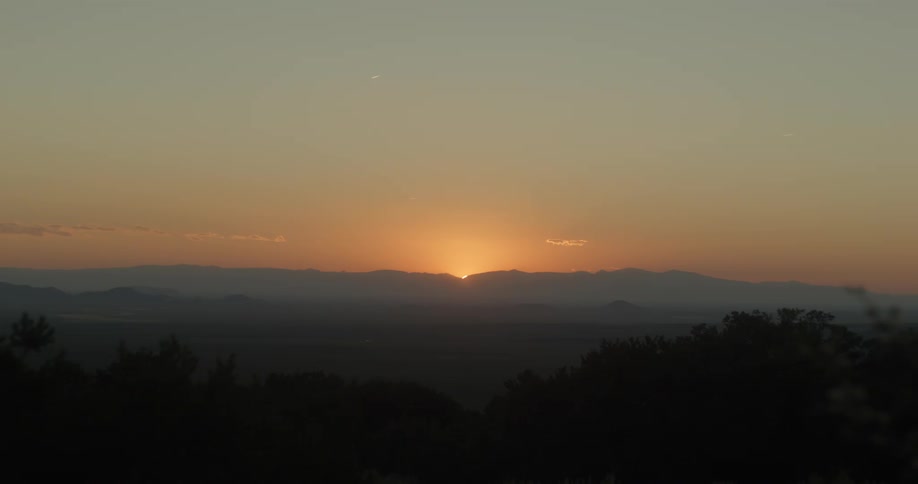 The sun dips below the horizon behind a mountain range