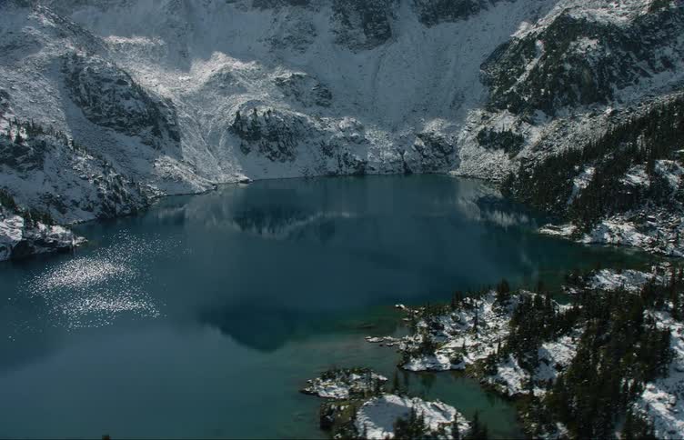 Aerial view of a lake nested in the snow covered slopes of a mountain