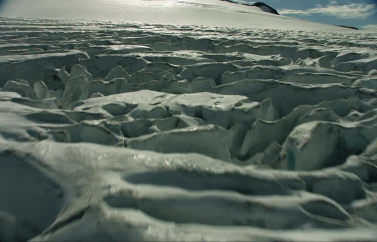 Ice covered ground leads to mountain under cloudy sky
