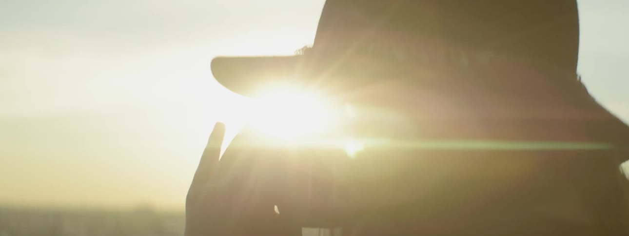 A woman takes pictures outside at sunset