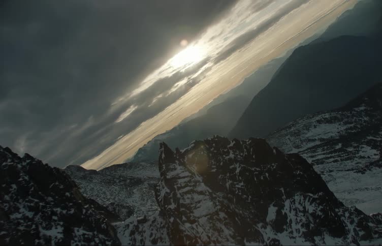 Aerial view of snow covering the slopes of a mountain range at sunset