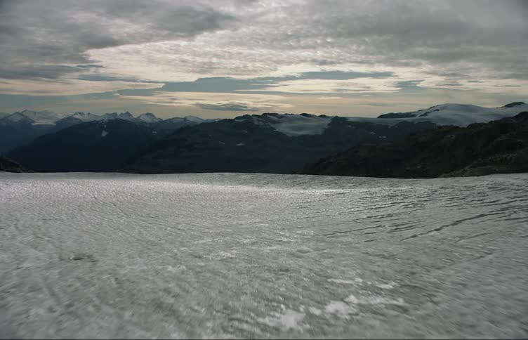 Aerial view of plains covered in snow near a dark mountain range