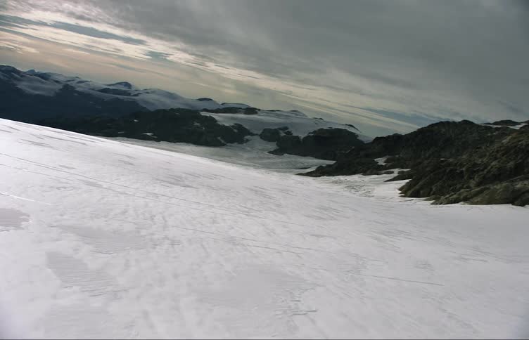 Thick snow covers slope and plains leading toward mountains