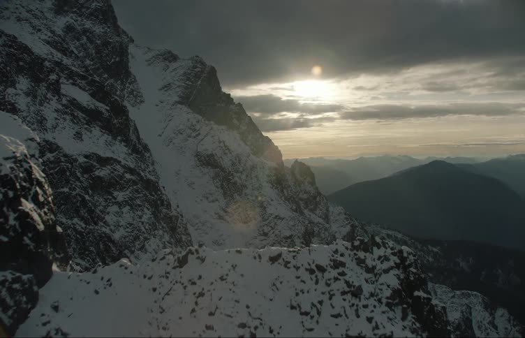 The snow covered mountain is overcast with a cloudy sky