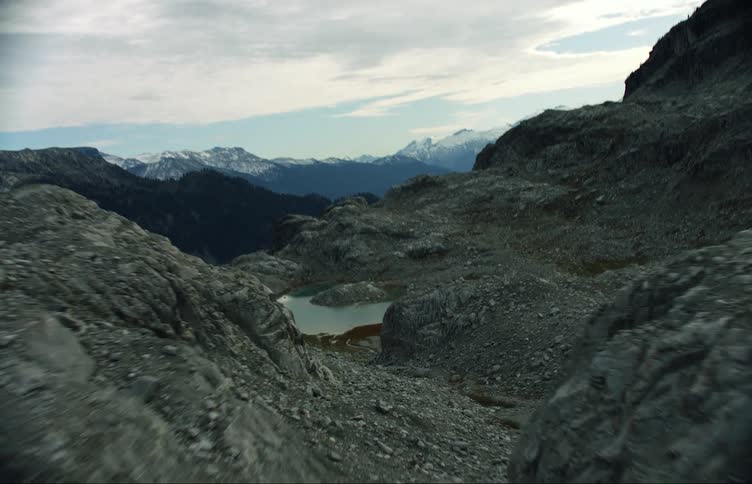 A mountain range covered in snow and ice with the sky and clouds in the background