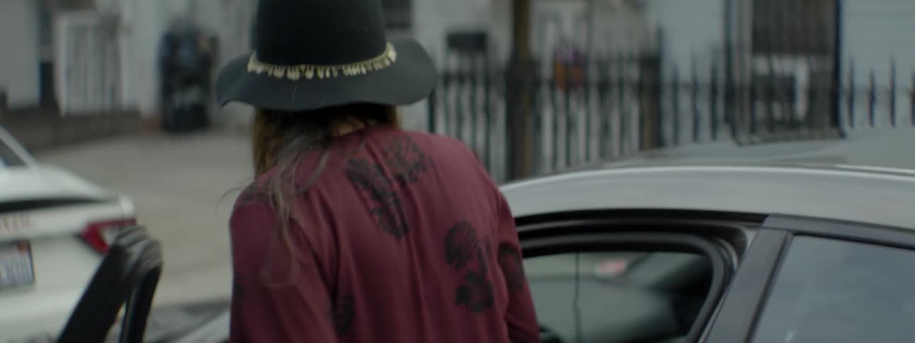 A woman in a purple shirt gets into a car