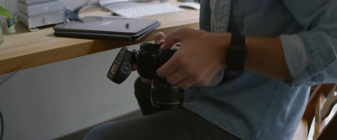 A man sitting at a table with a camera and a tablet in front of a computer