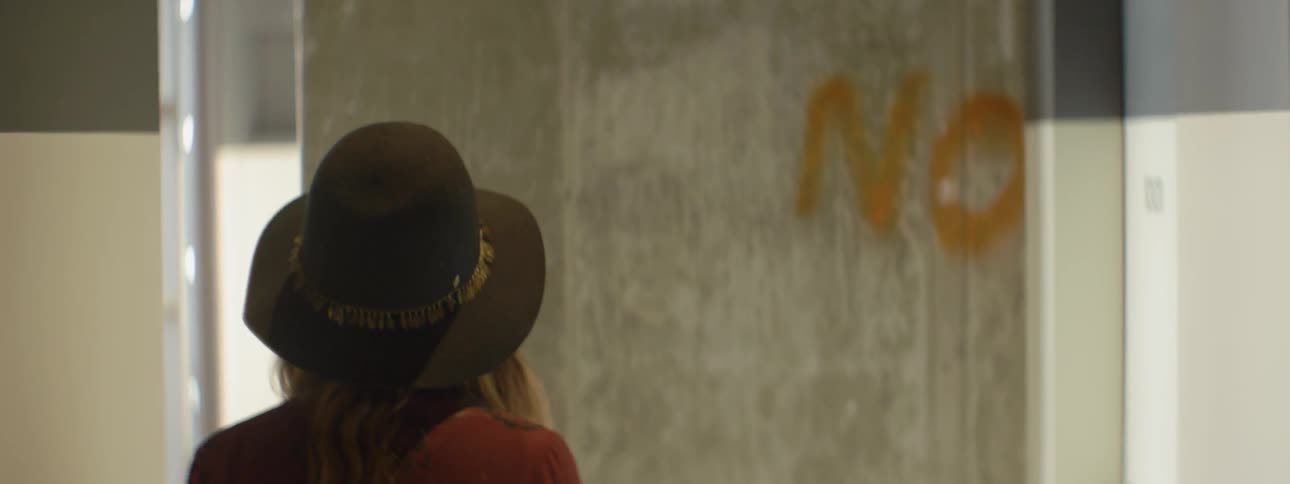 A woman walks towards a concrete wall with graffiti on it