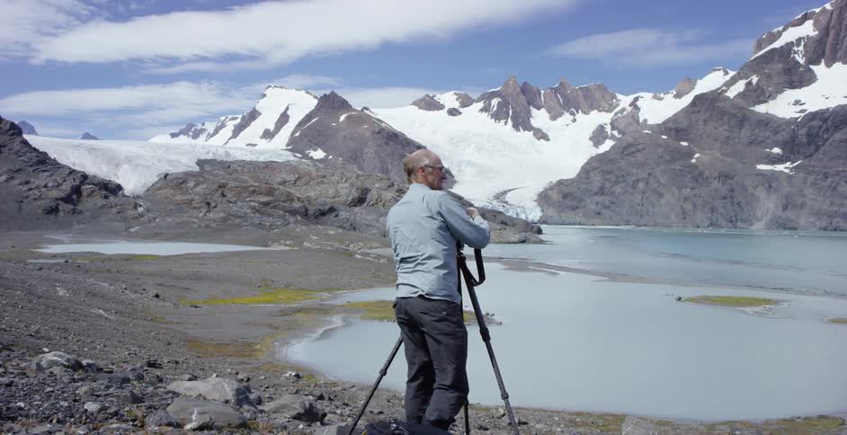Man taking pictures of a snowy wilderness from his camera on a tripod
