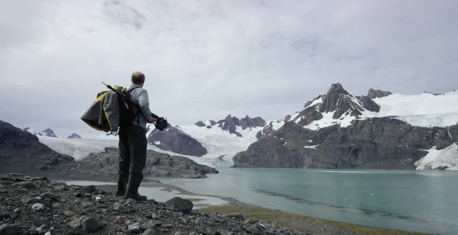 Man carrying equipment stands overlooking the beautiful scenery