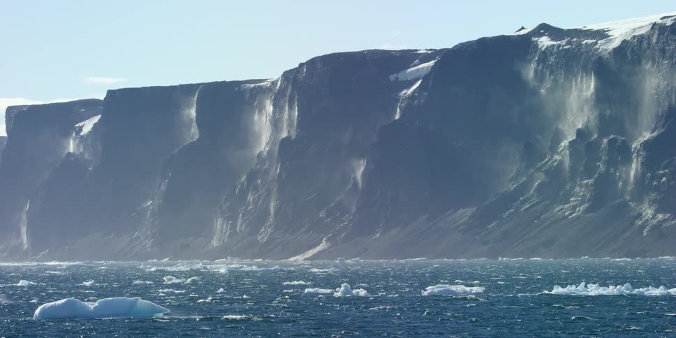 Chunks of ice floating  with large mountains in the background
