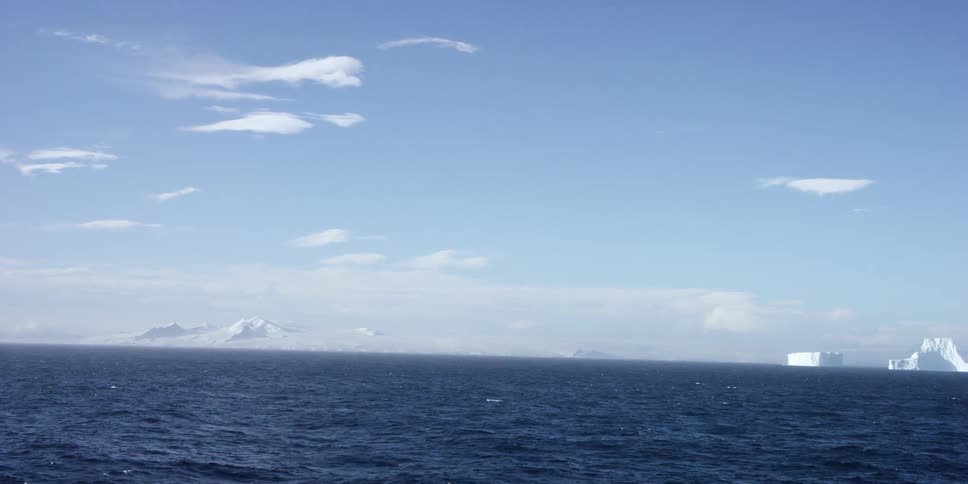 Cold ocean waters with snow covered mountains in the distance