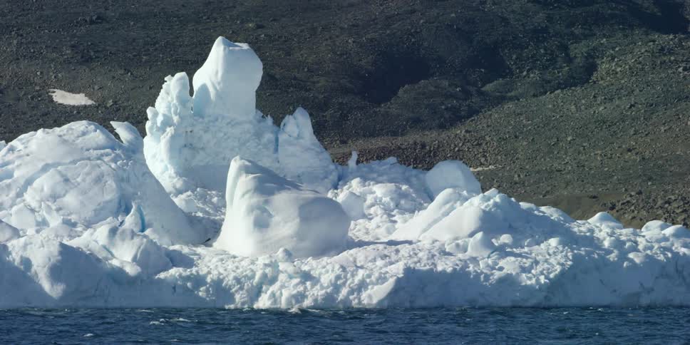 A large and tall glacier floats on the water