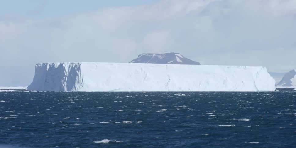 A large ice wall sits in rough waters