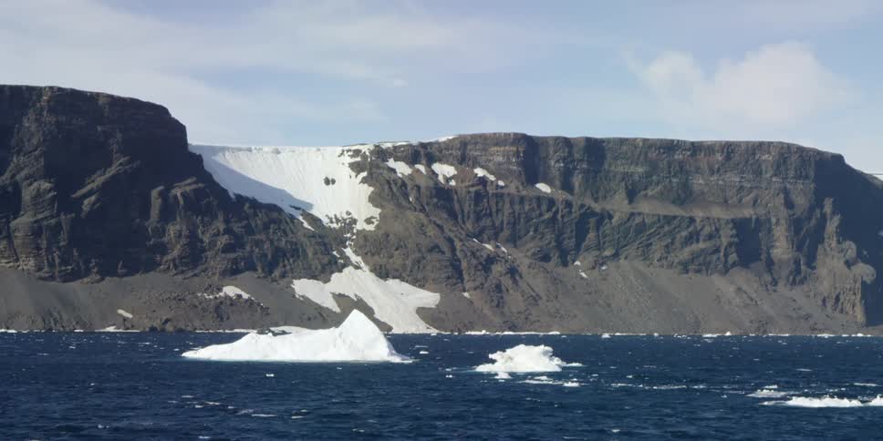 Icebergs float in the water near a mountain