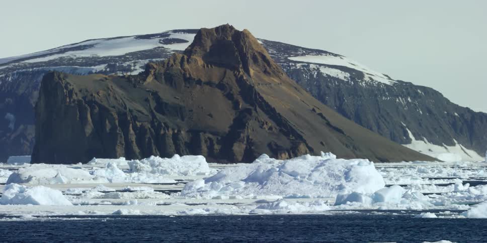 Ice floats in the water near some hills