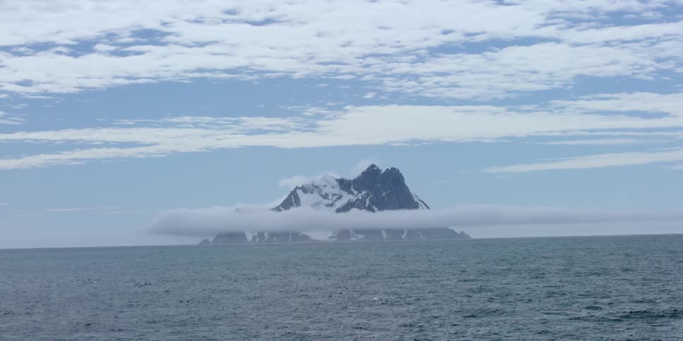 A mountain poking up out of a body of water
