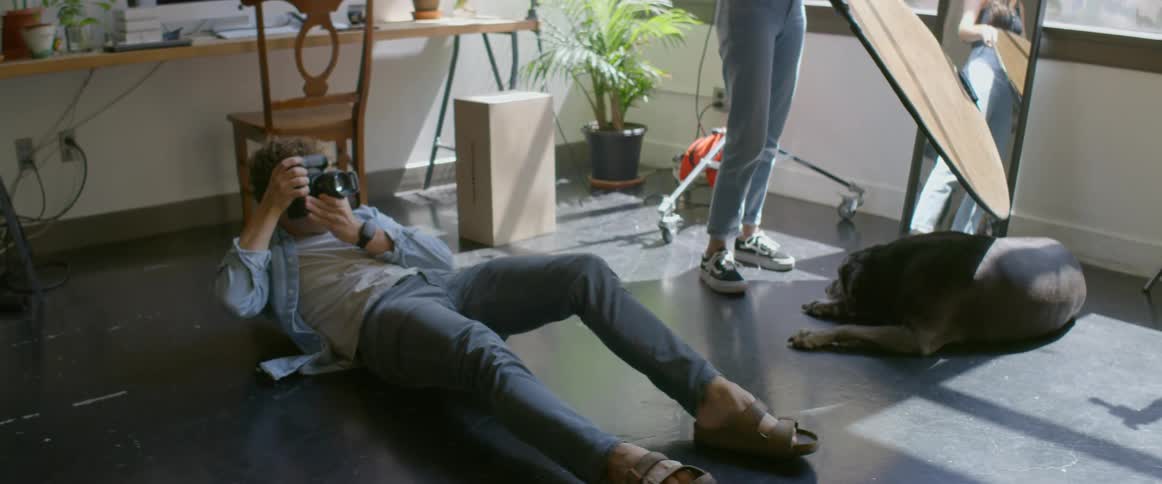 Photographer laying on the floor of an apartment taking pictures with a camera