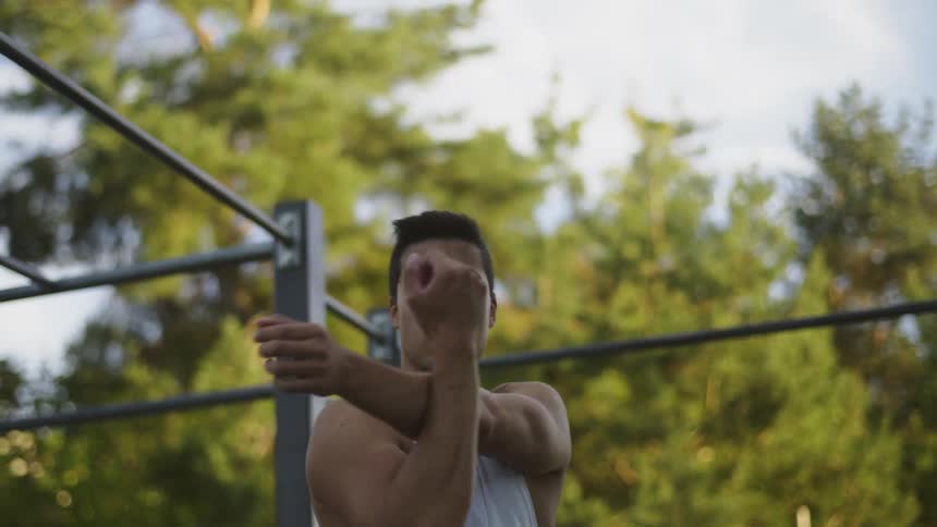 A man stretches his upper body while standing outdoors during the day