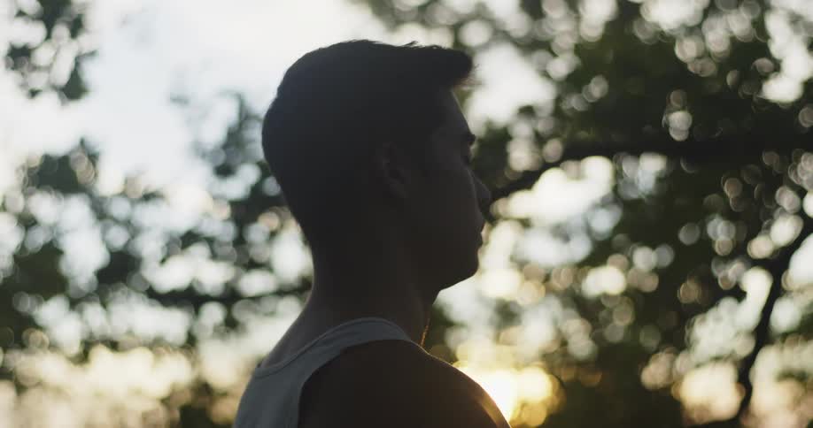 Silhouette of the head of a man sitting on a yoga pose outdoors at morning