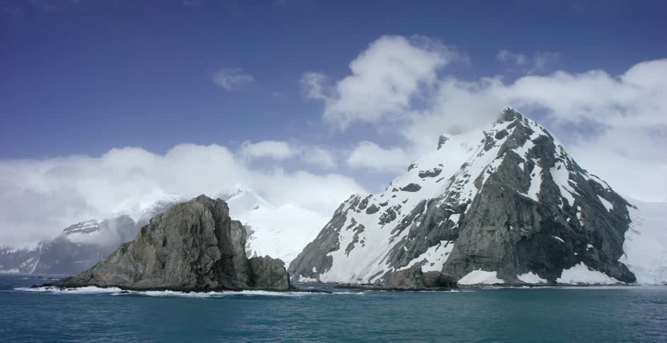 Snow-covered mountain as seen from the water on a cloudy day