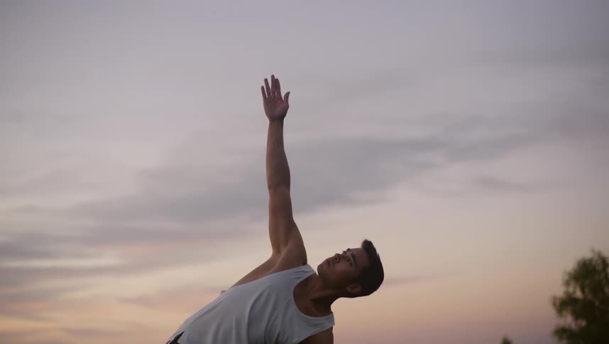 Man moves through yoga poses outdoors under red tinted sky
