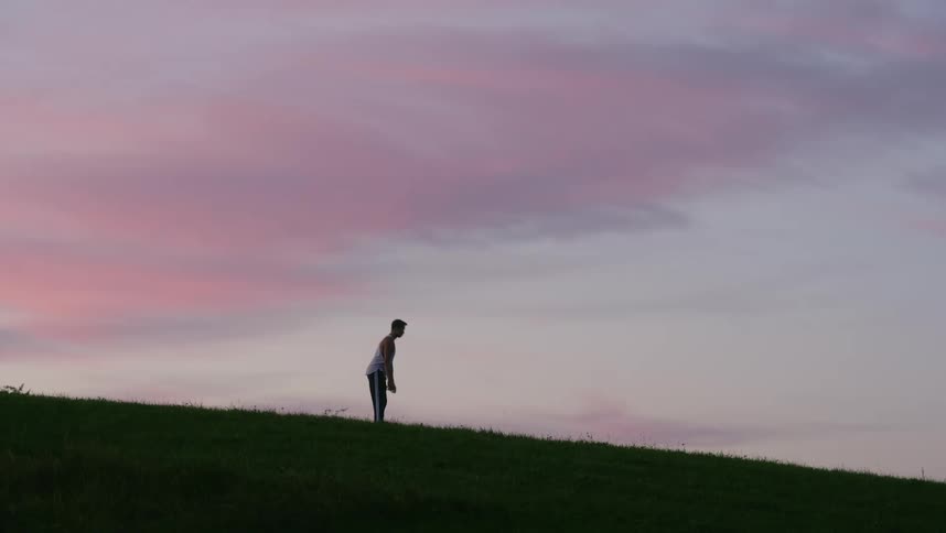 Silhouette of a man waving a towel in the air and laying it on the ground