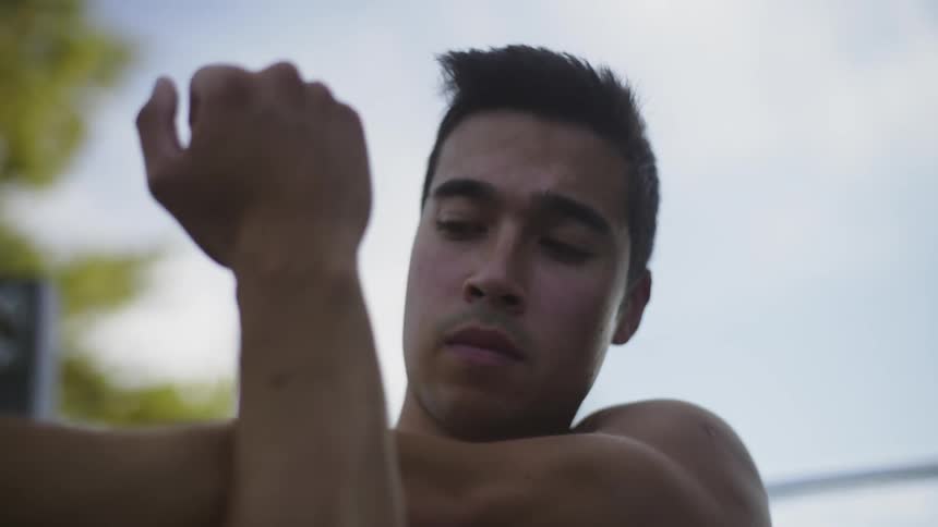 A man stretches his arms while standing outdoors during the day