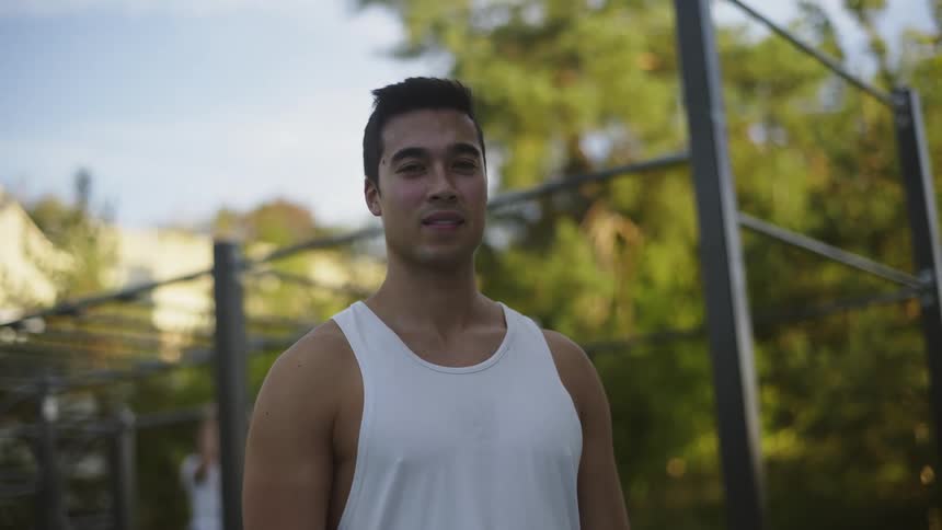 A man poses in front of the pull up bars in the park
