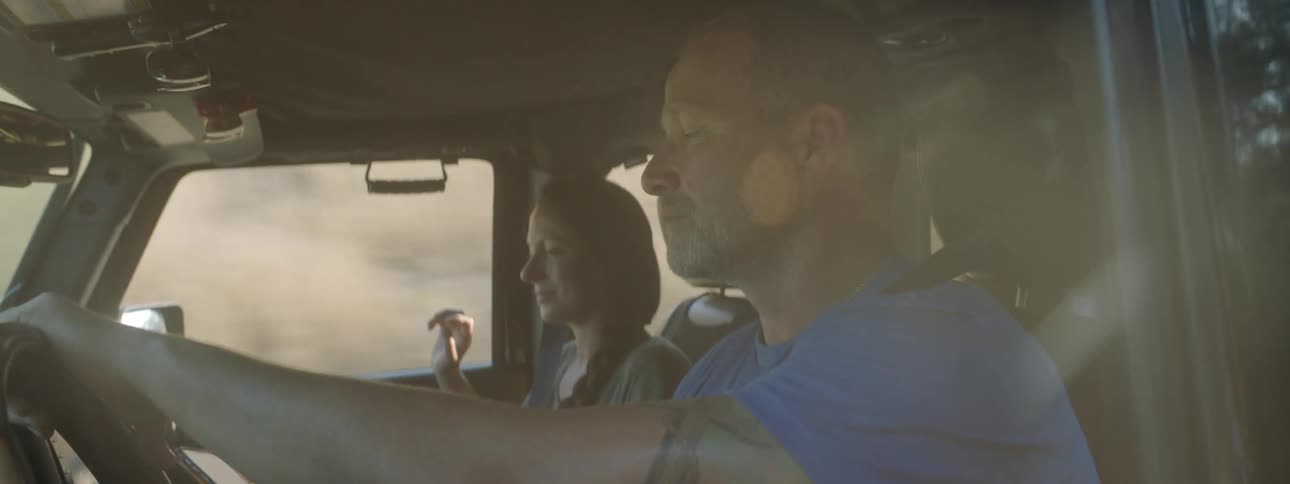 Young couple talking and smiling while driving a car through the countryside