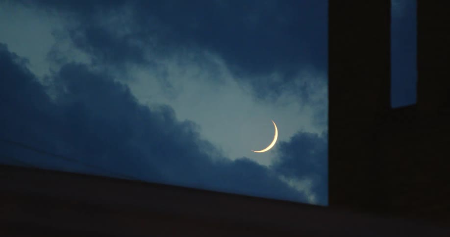 A pillar with the moon the sky and clouds in the background