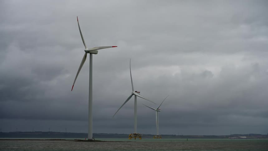 Wind turbines spinning under the clouds on a field at daytime