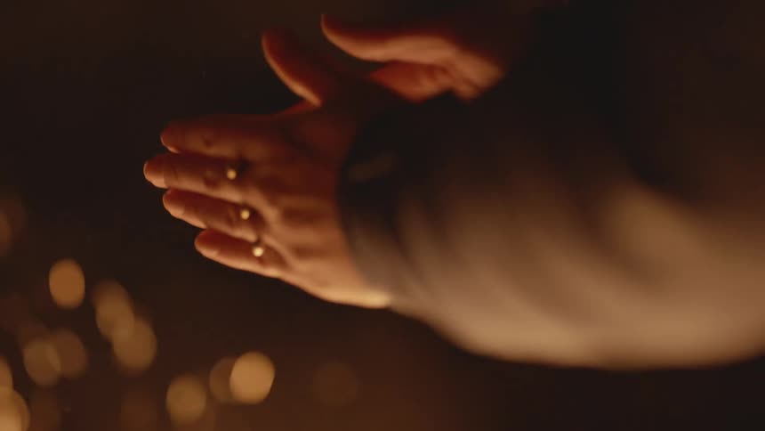 Man warms his hands over a fire at night outdoors