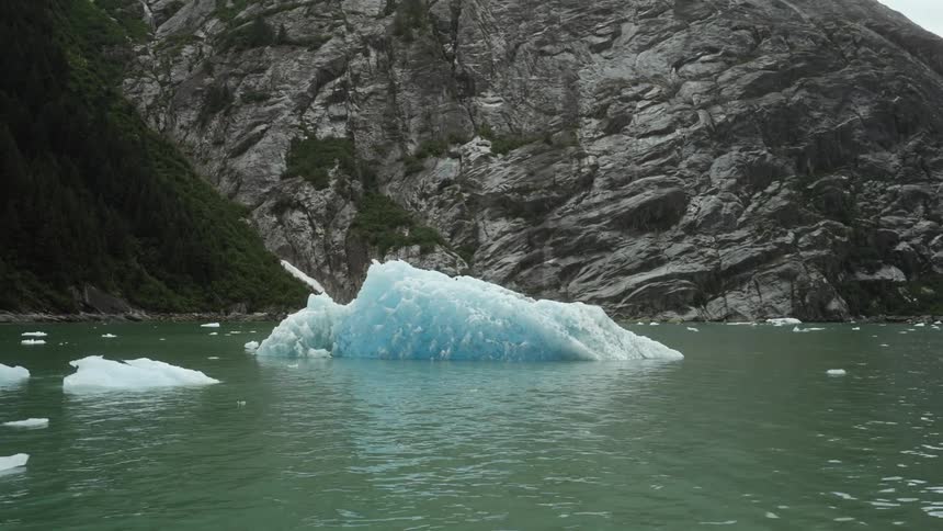 Floating iceberg in the ocean in front of the mountain