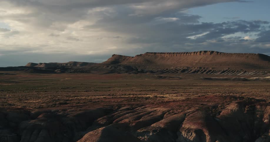 Aerial view of the desert badlands plains in front of the mountains at sunset