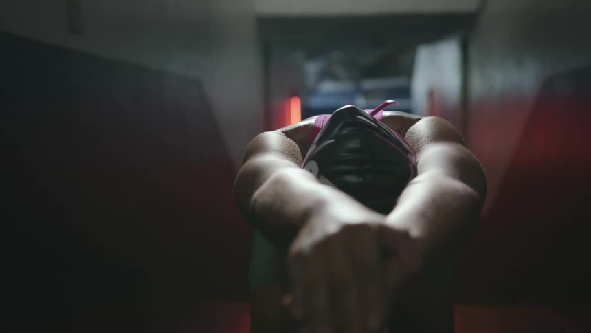 Woman wearing swim gear stretches in a corridor with yellow flashing lights