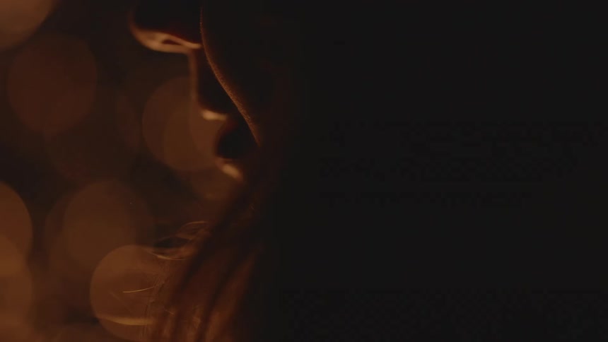 Silhouette of the face of a young woman sitting in front of a campfire talking at night