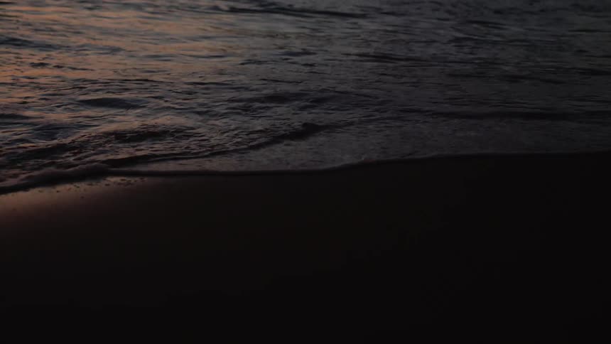 Waves crash onto the beach at sunrise