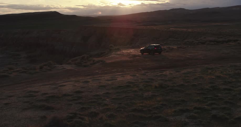 Suv sits parked on ground near cliff on cloudy day