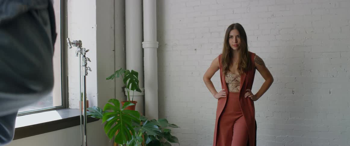 Photographers takes pictures of a female model in front of a white brick wallion